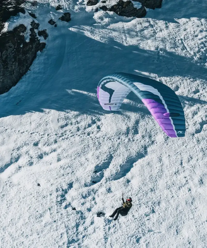 Koyot 6 couleur Blueberry en vol au dessus de pente enneigée